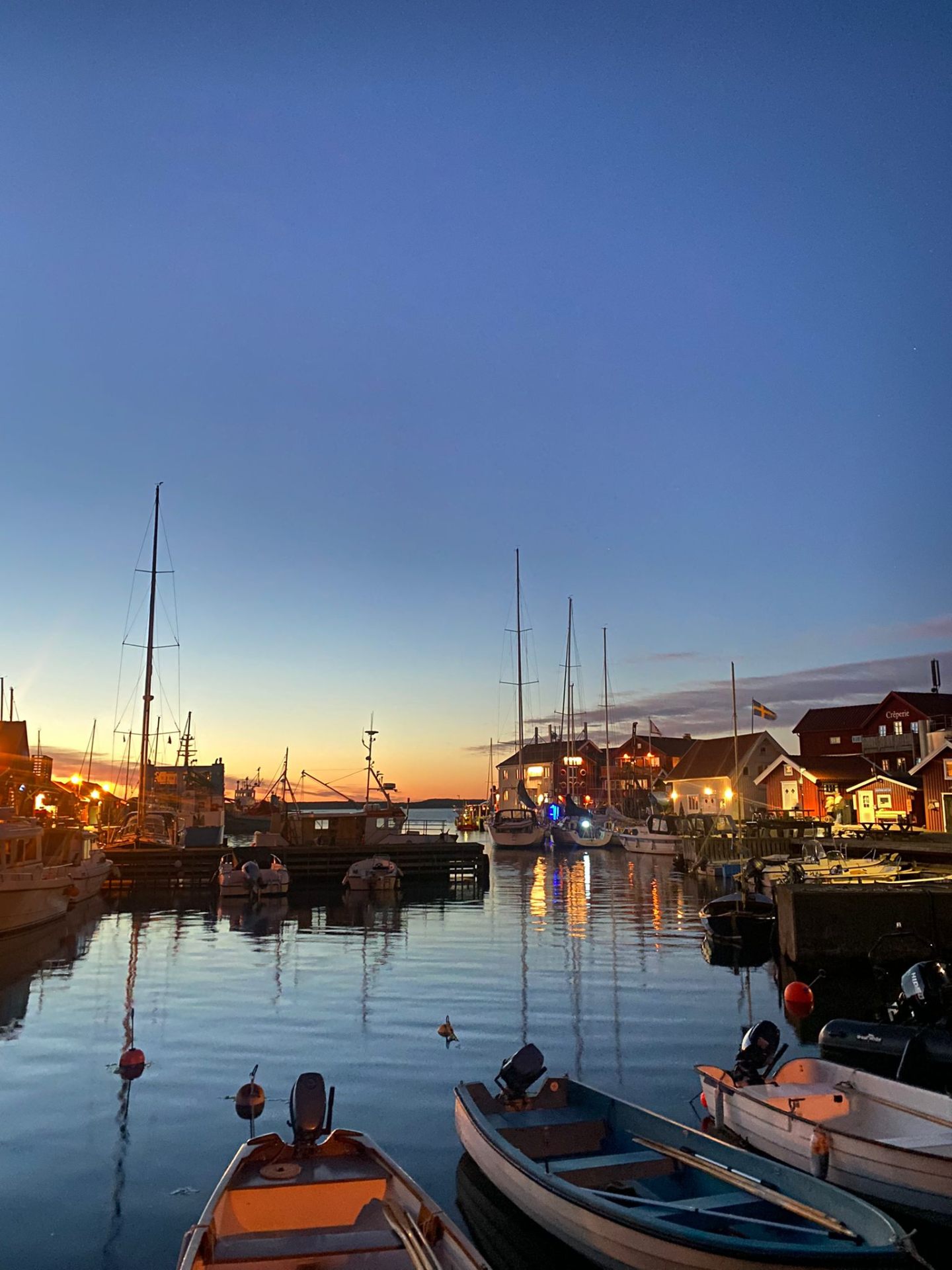 Kärringön harbour at dusk with sailboats and red boathouses